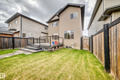 Rear exterior featuring beige horizontal siding, a ground-level deck with dark-framed railing, and a stone paver patio - 5308 164 Avenue, Edmonton, AB 