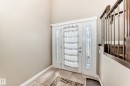 Double entry doors with decorative glass sidelights, ceramic tile flooring, and a carpeted staircase with wrought iron balusters - 5308 164 Avenue, Edmonton, AB 