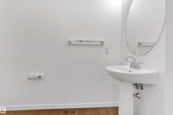 Wall-mounted ceramic sink with chrome faucet, complemented by a round frameless mirror - 