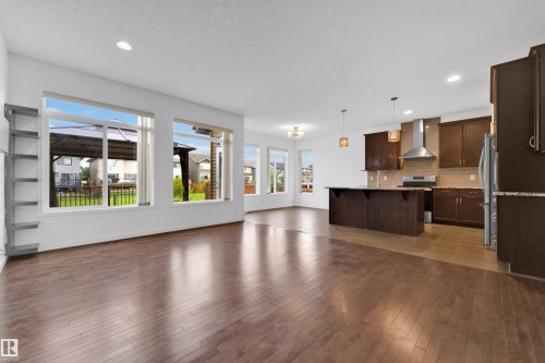 Open-concept living space featuring wood-finish flooring, recessed lighting, and large windows - 5432 20 Avenue, Edmonton, AB 