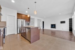 Open-concept living space with a kitchen island, recessed lighting, and a modern fireplace - 