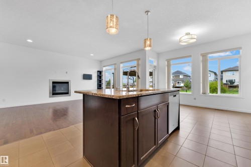 Central kitchen island with a stone countertop, integrated sink, and dishwasher - 5432 20 Avenue, Edmonton, AB 