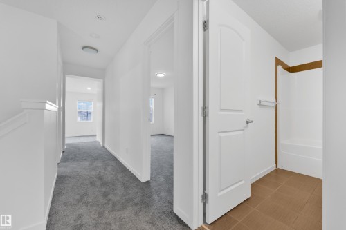 Hallway featuring gray carpeting, white painted walls, recessed lighting, and a white stair railing - 5432 20 Avenue, Edmonton, AB 