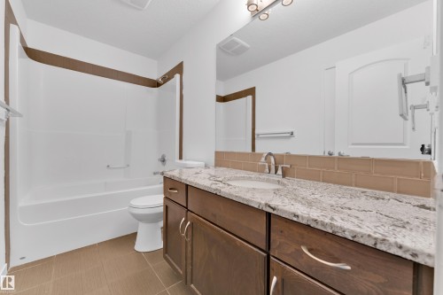 Bathroom featuring a single vanity with a granite countertop, undermount sink, and dark wood cabinetry - 5432 20 Avenue, Edmonton, AB 