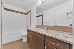 Bathroom featuring a single vanity with a granite countertop, undermount sink, and dark wood cabinetry - 