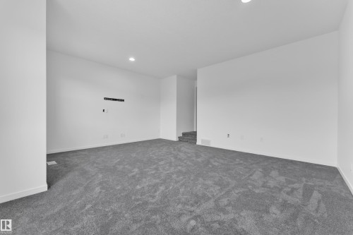 Spacious room featuring gray carpet, white walls, recessed lighting, and white baseboards - 5432 20 Avenue, Edmonton, AB 