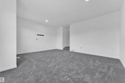 Spacious room featuring gray carpet, white walls, recessed lighting, and white baseboards - 