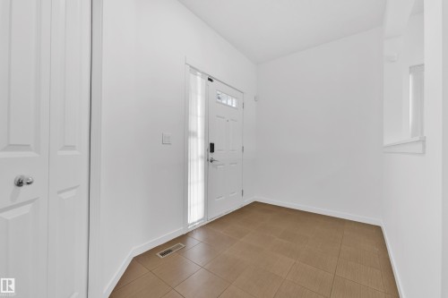 Entryway featuring a white paneled door with glass inserts, a full-length sidelight, and brown square tile flooring - 5432 20 Avenue, Edmonton, AB 