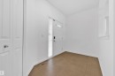 Entryway featuring a white paneled door with glass inserts, a full-length sidelight, and brown square tile flooring - 5432 20 Avenue, Edmonton, AB 