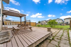 Expansive backyard deck featuring a gazebo structure, wood picket fencing, and chain link fencing - 
