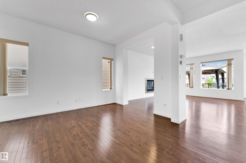 Spacious interior featuring wood-finish flooring, white walls, and multiple windows with blinds - 5432 20 Avenue, Edmonton, AB 