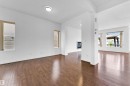 Spacious interior featuring wood-finish flooring, white walls, and multiple windows with blinds - 5432 20 Avenue, Edmonton, AB 