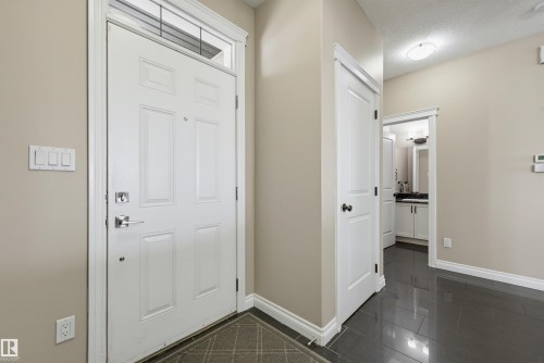 Entryway featuring a white paneled door with transom, chrome hardware, light neutral walls, and dark glossy tile flooring - 21928 97 Avenue, Edmonton, AB 
