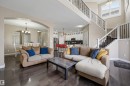 Open-concept interior featuring wood-finish flooring, a two-story ceiling, and a staircase with wrought iron balusters - 21928 97 Avenue, Edmonton, AB 