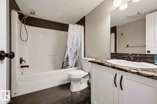 Bathroom featuring a white tub/shower combination, dark bronze fixtures, and a vanity with a patterned countertop - 21928 97 Avenue, Edmonton, AB 