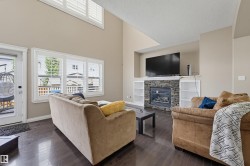 Living room with vaulted ceiling, wood-finish flooring, and a stone-clad fireplace with built-in shelving - 