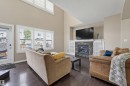 Living room with vaulted ceiling, wood-finish flooring, and a stone-clad fireplace with built-in shelving - 21928 97 Avenue, Edmonton, AB 