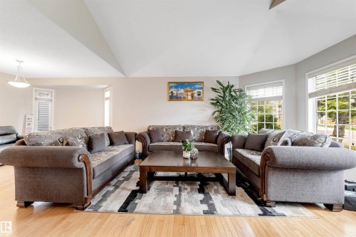 Spacious living area featuring light wood-finish flooring, abundant natural light from multiple windows, and a vaulted ceiling - 4465 32A Street, Edmonton, AB 