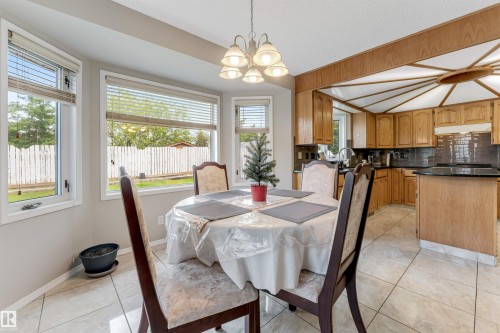 Dining area featuring a bay window, a multi-light chandelier, and tiled flooring - 4465 32A Street, Edmonton, AB 