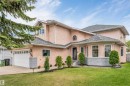 Stucco exterior residential property featuring a double garage, multiple arched windows, and a prominent bay window - 4465 32A Street, Edmonton, AB 