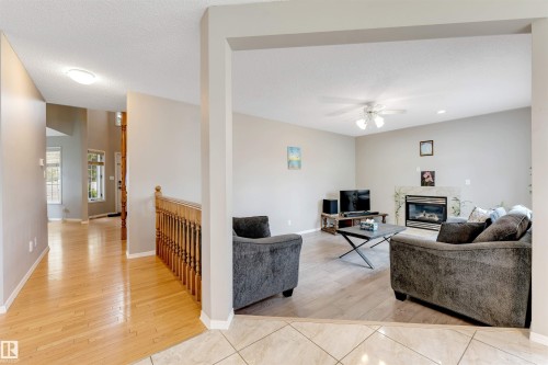 Bright living area featuring a fireplace with a stone surround, a ceiling fan, and light-toned walls - 4465 32A Street, Edmonton, AB 