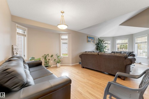 Spacious living area featuring light wood-finish flooring and ample natural light from multiple windows - 4465 32A Street, Edmonton, AB 