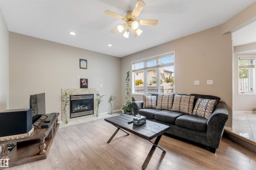 Living area featuring wood-finish flooring, a contemporary fireplace with a stone surround, and multiple recessed lights - 4465 32A Street, Edmonton, AB 