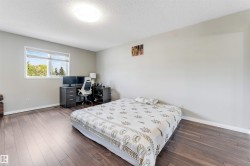 Spacious room featuring wood-finish flooring, a large window, light-toned walls, and a ceiling-mounted light fixture - 