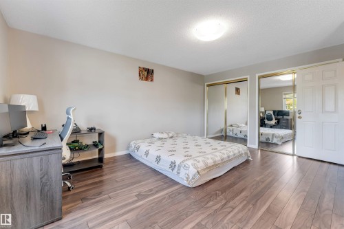 Spacious room featuring wood-finish flooring, light grey wall tones, and overhead flush mount lighting - 4465 32A Street, Edmonton, AB 
