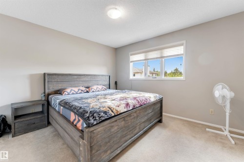 Bedroom featuring a large window with white blinds, neutral wall paint, and carpet flooring - 4465 32A Street, Edmonton, AB 