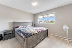 Bedroom featuring a large window with white blinds, neutral wall paint, and carpet flooring - 