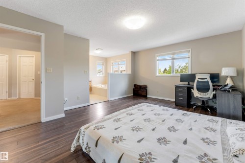 Spacious room featuring dark wood-finish flooring, light neutral-toned walls, and multiple windows providing natural illumination - 4465 32A Street, Edmonton, AB 