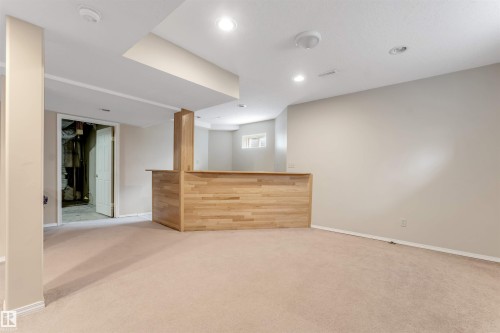 Spacious room featuring a light wood-finish built-in bar, recessed lighting, neutral carpeting, and painted walls - 4465 32A Street, Edmonton, AB 