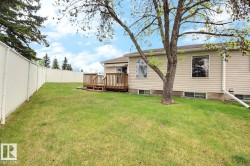 Expansive backyard featuring a manicured lawn, a two-tier wood deck, and mature trees - 