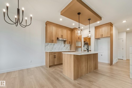 Modern kitchen featuring light wood-finish cabinetry, white countertops, and a white marble-look backsplash - 4636 18 Avenue, Edmonton, AB 