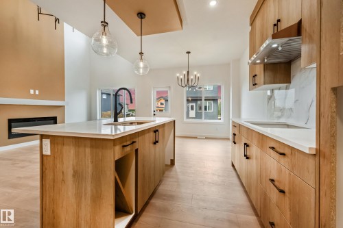 Contemporary kitchen island with a built-in sink and matte black faucet - 4636 18 Avenue, Edmonton, AB 