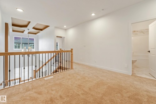 Carpeted upper-level landing featuring a wood and metal baluster railing - 4636 18 Avenue, Edmonton, AB 
