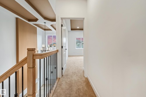 Staircase featuring wood handrails and black metal balusters - 4636 18 Avenue, Edmonton, AB 