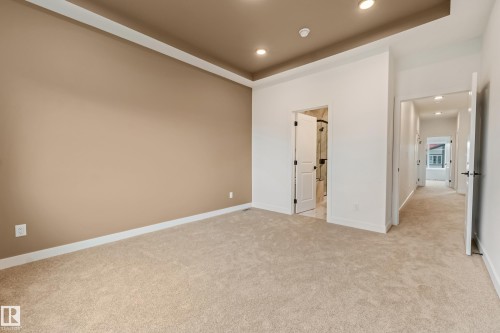 Spacious room featuring neutral carpeting, a tray ceiling with recessed lighting, and a two-tone paint scheme - 4636 18 Avenue, Edmonton, AB 