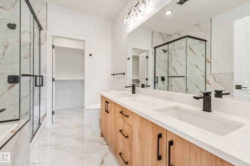 Dual vanity with wood-finish cabinetry and matte black hardware, featuring integrated rectangular sinks and white countertops - 4636 18 Avenue, Edmonton, AB 