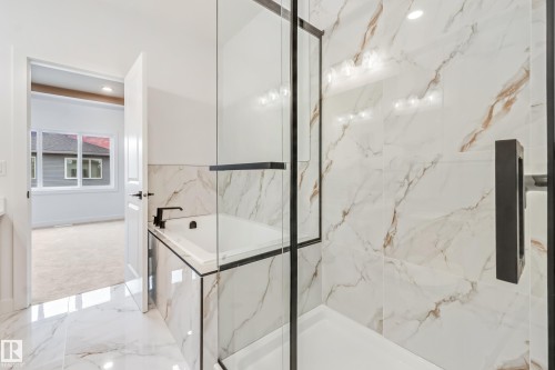 Walk-in shower featuring a frameless glass enclosure and matte black fixtures - 4636 18 Avenue, Edmonton, AB 