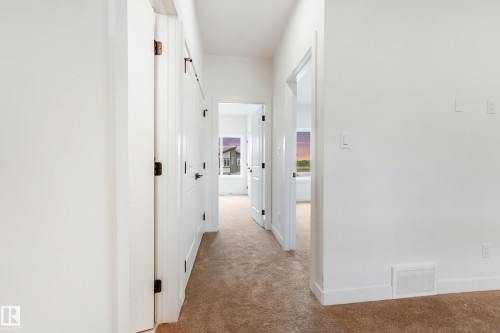 Hallway featuring neutral-toned carpeting, white walls, and white trim - 4636 18 Avenue, Edmonton, AB 