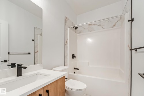 Bathroom featuring a single vanity with wood-finish cabinetry, a white countertop, and a rectangular undermount sink - 4636 18 Avenue, Edmonton, AB 