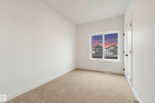Carpeted room with a white framed window and white walls - 4636 18 Avenue, Edmonton, AB 