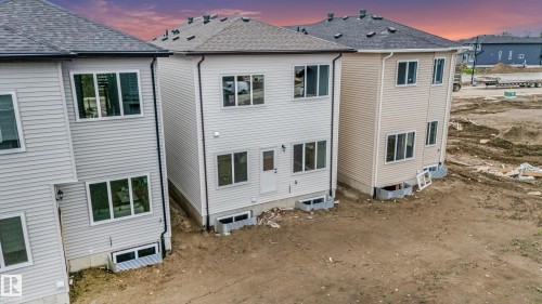 New construction home featuring light-colored horizontal siding, a dark shingle roof, and multiple large windows - 4636 18 Avenue, Edmonton, AB 