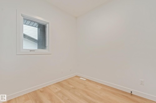 Crisp white walls frame a modern window with a single pane, complemented by light wood-finish flooring and white baseboards - 4636 18 Avenue, Edmonton, AB 