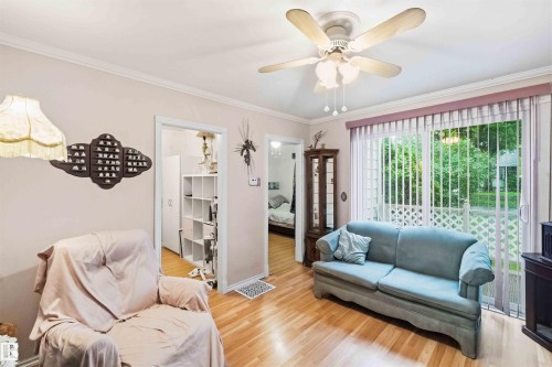 Bright interior space featuring wood-finish flooring and a ceiling fan with integrated lighting - 12016 61 Street, Edmonton, AB 