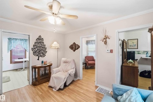 Interior space featuring wood-finish flooring, white crown molding, and a ceiling fan with integrated lighting - 12016 61 Street, Edmonton, AB 