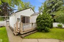 White-sided exterior with a covered porch featuring lattice railing, sliding glass entry, and concrete pathway - 12016 61 Street, Edmonton, AB 