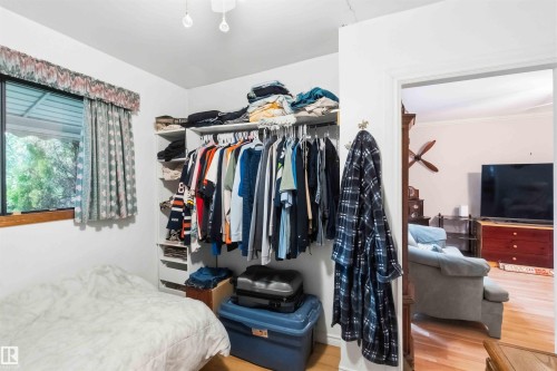 Bedroom with light-toned wood-finish flooring, a window offering exterior views, and a built-in closet organization system - 12016 61 Street, Edmonton, AB 